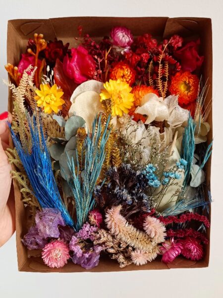flores desidratadas coloridas dispostas em uma caixa de papel kraft